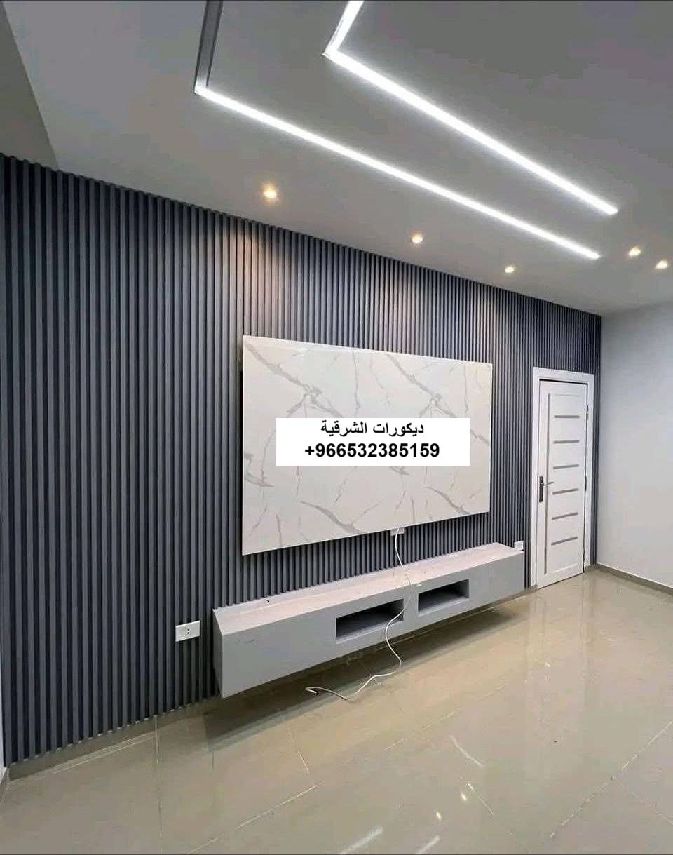 تركيب خلفية تلفزيون مودرن تجمع بين بديل الرخام الأبيض وبديل الخشب البني مع إضاءة ليد مخفية في فيلا بالدمام - تنفيذ ديكورات الشرقية.